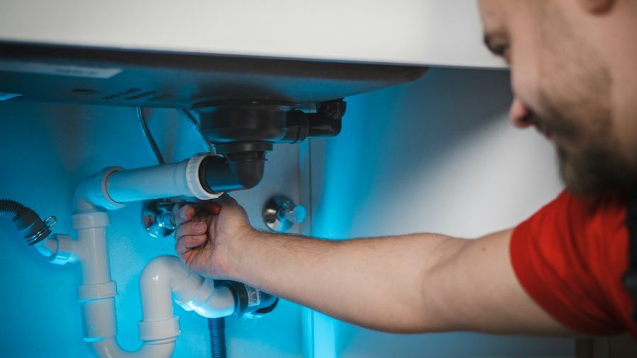 Plumber fixing pipes under a sink